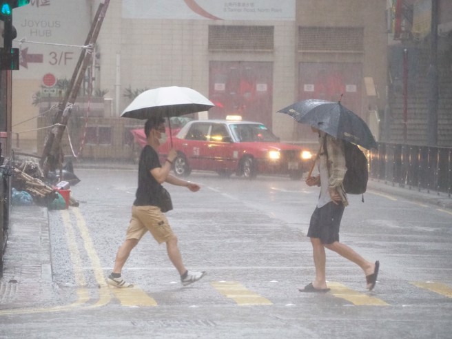 8日清晨虽下着滂沱大雨，仍有香港民眾冒雨外出。（中通社）