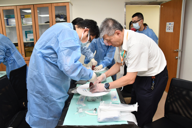 指導老師們對醫師們進行心室輔助器置放模擬縫合的手把手教學。（臺大雲林分院提供）