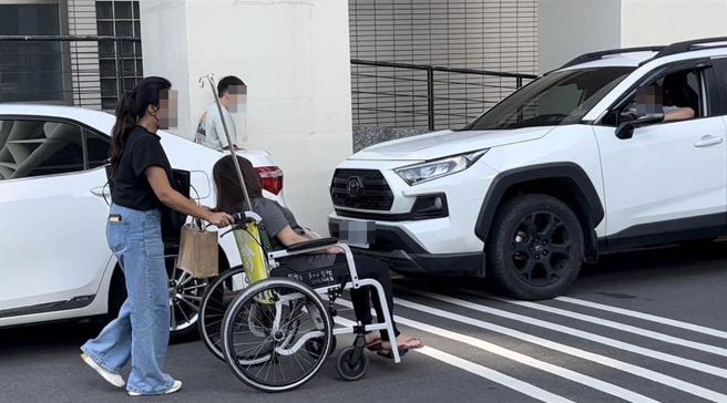 郑姓中尉母亲从急诊室走出，虚弱到需要坐轮椅回到车上。（崔正纲摄）