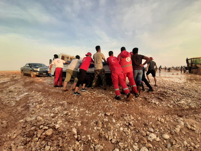 2023年9月11日，利比亞紅新月會成員在利比亞受洪水影響的地區推著一輛卡車穿過泥濘。（路透社）