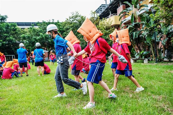 国立新竹特殊教育学校地震避难掩护演练，特殊生戴上安全头套，由老师带着到操场避灾。（罗浚滨摄）