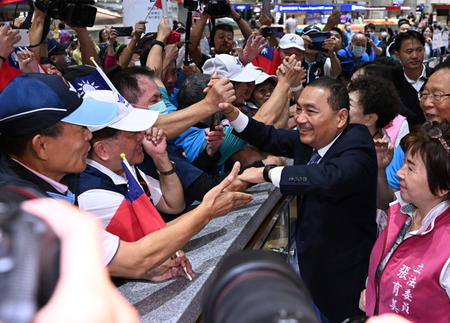 侯友宜（右）结束8天的访美行程于22日凌晨4时26分返抵桃园国际机场，多位党籍立委、市议员接机，在入境时也有逾百名支持者在入境大厅手摇国旗接机欢迎、侯友宜也上前与支持者热情握手互动。（陈麒全摄）