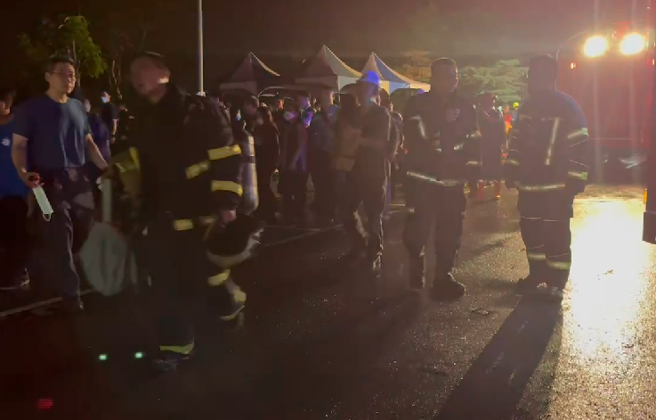 屏东明扬国际爆炸不断「火势扩大延烧」，警消暂撤离侧门以外。(林和生翻摄)