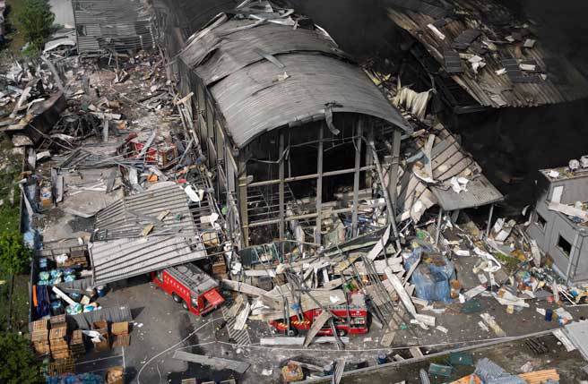 屏东科技产业园区明扬高尔夫球厂22日发生爆炸，火场今日持续闷烧，三部救火的消防车在爆炸中被埋在瓦砾堆中。（黄子明摄）