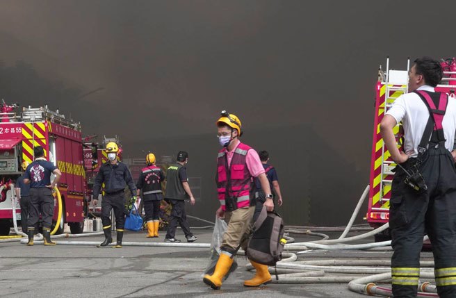 屏東科技園區22 日發生大火，至今日仍持續悶燒，造成多位消防員殉職，上午濃煙一度增大，現場指揮官考慮人員安全，一度下令救災人員撤退，打火弟兄帶著個人裝備，從濃煙中走出廠區外。（黃子明攝）