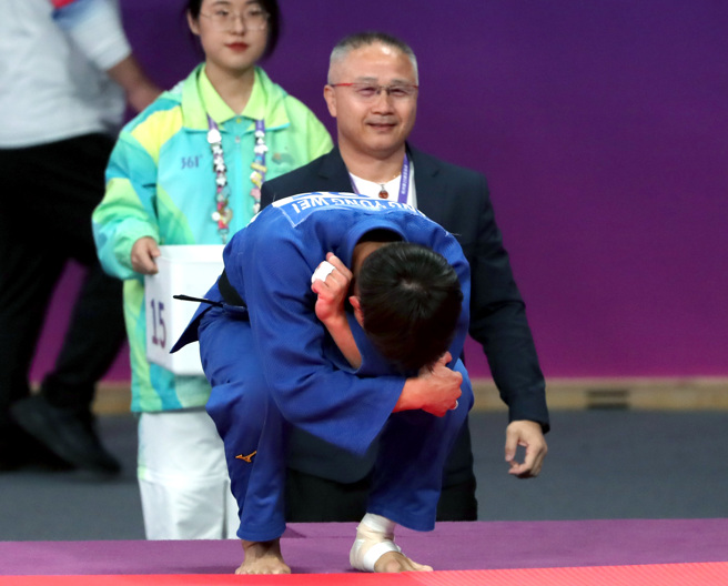 「柔道男神」杨勇纬夺下杭州亚运男子60公斤级金牌，教练刘文等（后）也为爱徒开心。（郑任南摄）