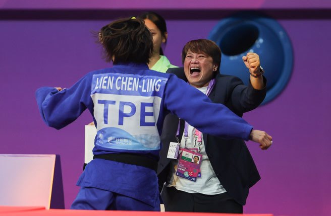 台湾「柔道女王」连珍羚（背对者）25日在杭州亚运女子57公斤级项目闯进金牌战，击败日本名将玉置桃，拿下金牌，赛后她衝下台与教练拥抱。(中央社)
