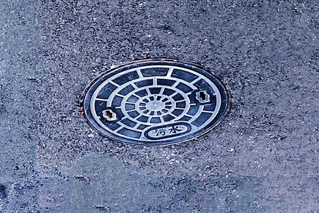 新竹县污水下水道使用费明年开徵，民眾可检房屋前或后邻接公共排水沟处，若有直径15公分标示「污水」字样的孔盖，即是有接管。（罗浚滨摄）