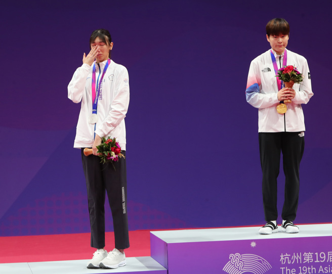 杭州亚运跆拳道国手林唯均（左）在女子53公斤级不敌韩国朴慧贞夺银，颁奖时仍在啜泣。（郑任南摄）