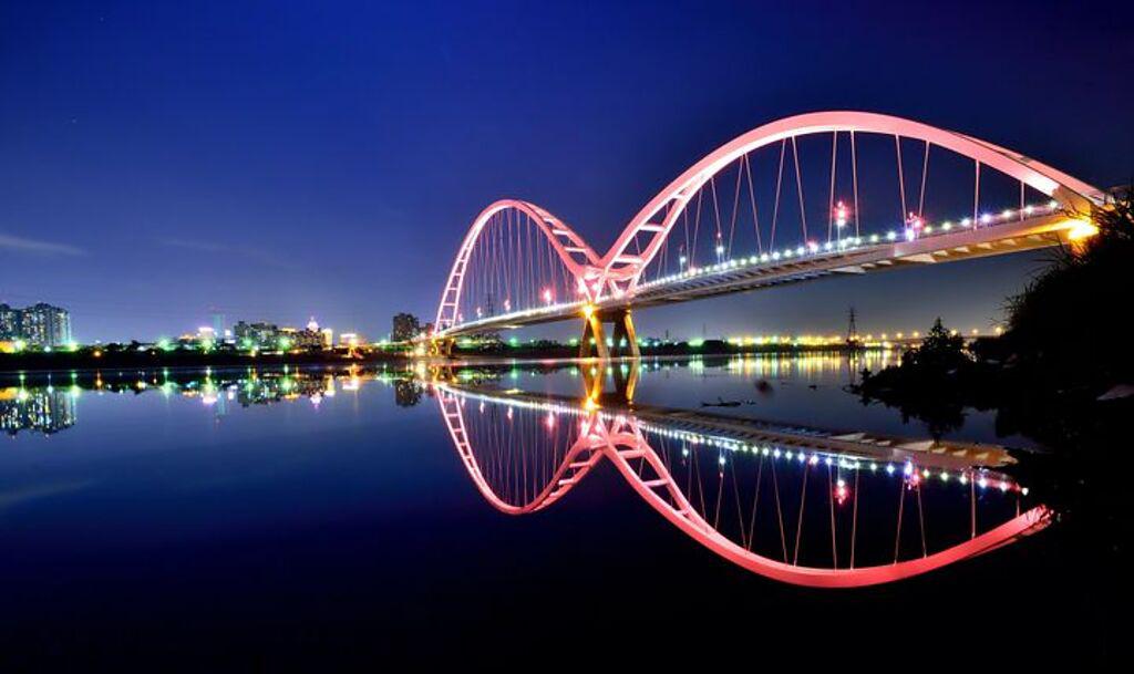 新月橋－點點霓虹照亮拱橋優美的弧形，倒映在河面上的景觀與夜空中的月光相互輝映。　圖：新北市政府觀光旅遊局／提供