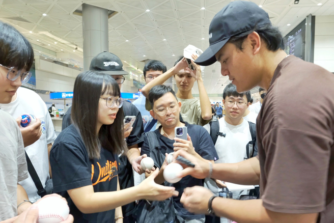 张育成（右）一一为球迷们签名并合影。（中央社）