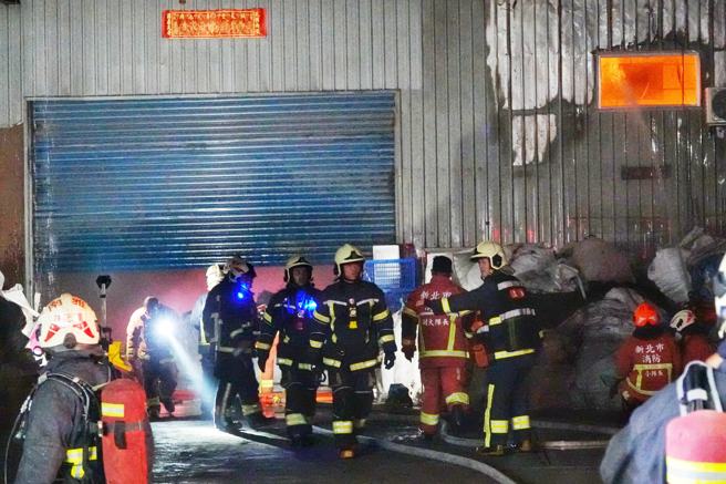 八里废五金回收场厂暗夜大火 ，大批警消忙射水灌救，铁皮厂房全面燃烧剩骨架 。(黄世麒摄)