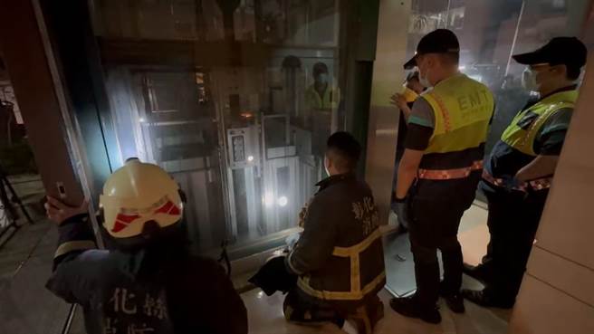 消防員與電梯維修人員在電梯外安撫受困夫妻的情緒。（民眾提供／孫英哲彰化傳真）