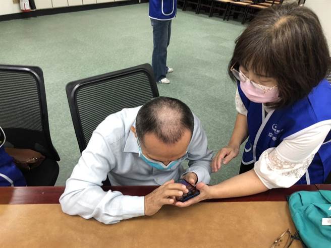 许多视障者是首次接触手机，必须一步步由专人协助操作。（翻摄照片／洪靖宜高雄传真）