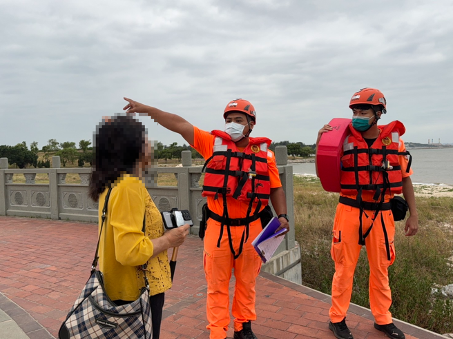 第九岸巡队人员在海边劝说游客勿进入警戒状态内观浪。( 笫九岸巡队提供)