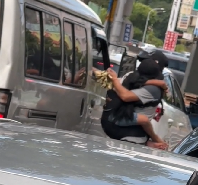 日前有民眾于抖音平台发布一则影片，一名男子于三重区一带，手抱女童，并趁车辆停等红灯之际，穿梭于车阵贩卖玉兰花。（ 翻摄画面/ 截自「抖音平台」）