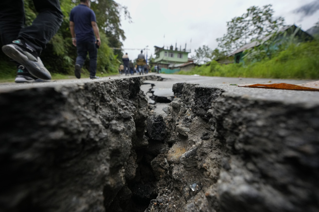 印度锡金省洪灾地区民眾7日沿着严重毁坏的道路步行，返回家园收拾残局。（美联社）