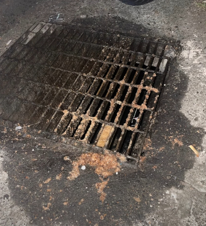 攝影師前往一看，發現水溝蓋上滿是油渣跟炸物碎屑。(圖／影片截圖)