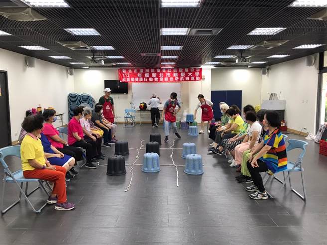 玩具银行活动老师利用童军绳画出九宫格，带领长辈利用不同顏色的露露椅玩圈圈叉叉游。（新北市社会局提供）