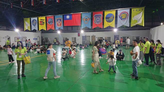 国庆晚会8日晚间在台南空军基地登场，因天空下起滂沱大雨，民眾躲进停机棚狼狈蹲坐在地上。（程炳璋摄）