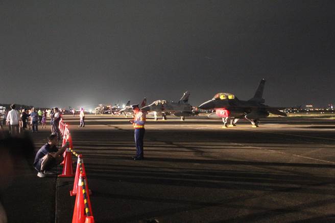 台南空军基地国庆晚会登场，跑道上的战机在夜空下一字排开，十分迷人，民眾拿起手机拍摄。（程炳璋摄）