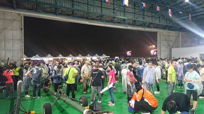国庆晚会8日晚间在台南空军基地登场，现场下起滂沱大雨，许多民眾被淋到受不了跑进停机棚内躲雨。（程炳璋摄）