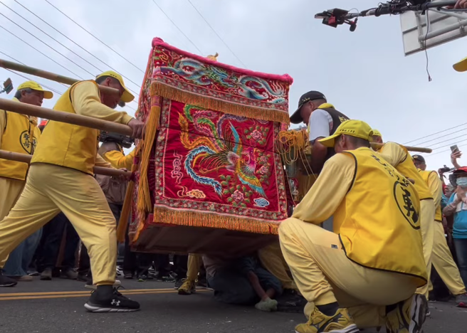 白沙屯妈祖的轿身微微倾斜摇晃，像在轻抚迟缓儿，赐福给她。(翻摄自YouTube《白沙屯妈祖网路电视台》)