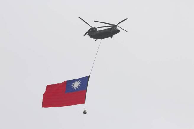 中华民国中枢暨各界庆祝112年国庆大会10日在总统府府前广场登场，悬挂巨幅国旗的CH-47SD契努克运输直升机，通过总统府上空。（张铠乙摄）
