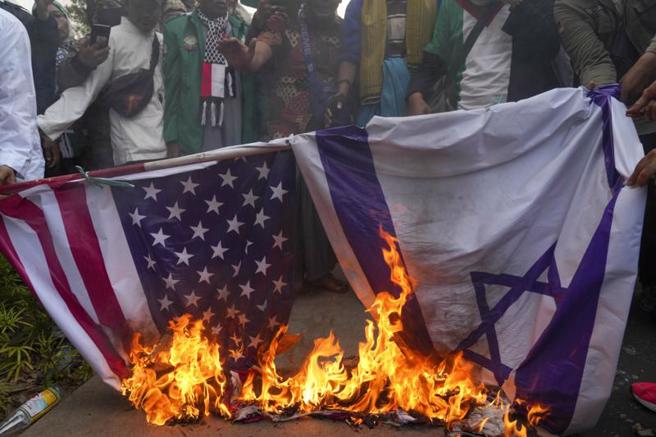 在印尼雅加達美國大使館外，穆斯林抗議者焚燒美國和以色列國旗。（美聯社）