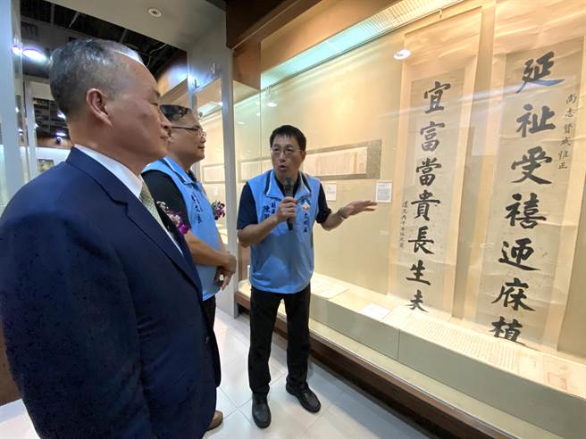 文化局副局长陈国兴(右)为罕见的八尺大对联「延祉受禧迎庥植福，宜富当贵长生未央」导览解说。(于家麒摄)