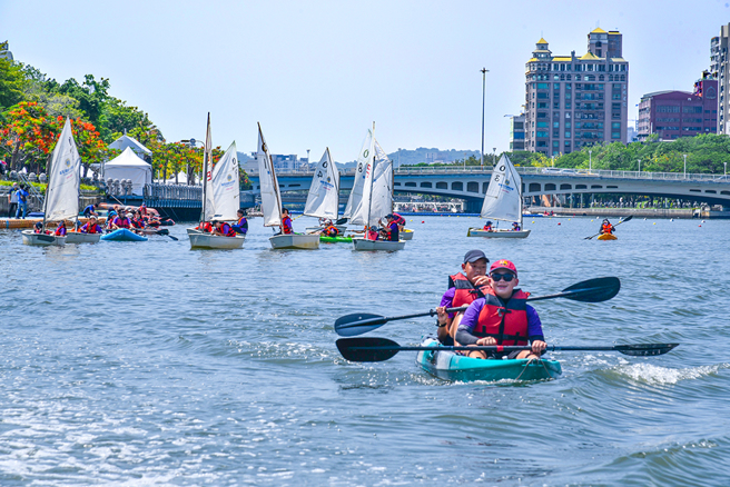 光荣国小毕业生驾着数十艘独木舟及帆船行驶于高雄城市地标之间，从海上欣赏高雄的美丽风景。(图片提供/高雄市盐埕区光荣国小)