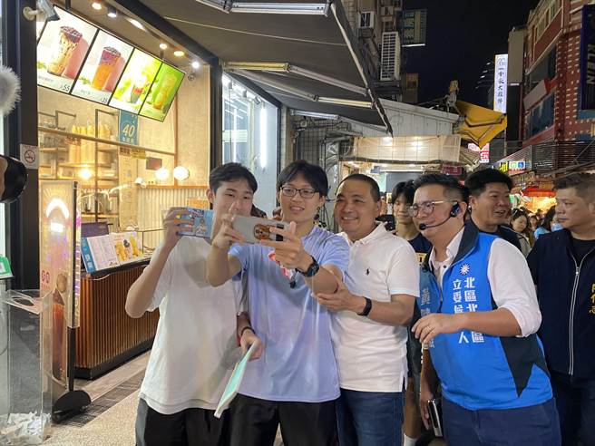 国民党总统参选人侯友宜今天到一中街扫街拜票，有不少年轻人主动找他自拍。（张亦惠摄）