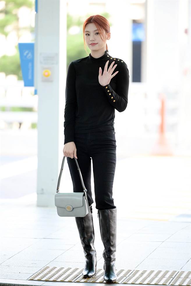 Yeji身穿秋冬系列钮扣针织衫搭配高筒香蕉靴2万2900元、浅花岩色Robinson漆皮两用肩背包1万7900元，现身机场。（TORY BURCH提供／林欣仪台北传真）