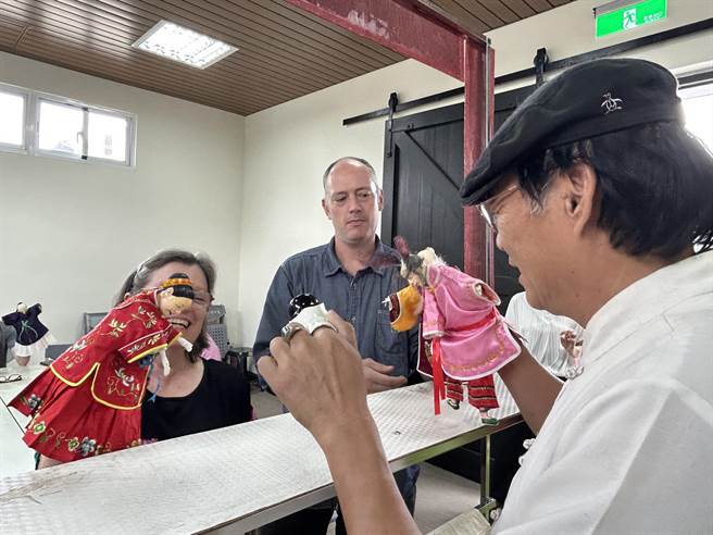 屏東潮州鎮創團逾一甲子的「明興閣掌中劇團」，以製偶帽、操偶守護文化產業的精神，連美國西北木偶中心館長Dmitri Carter（中）也敬佩，近日特別邀5名偶戲界前輩組團參訪。（謝佳潾攝）