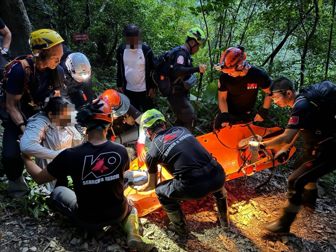 消防隊員協助將婦人運送下山送醫。（黃仲瑜翻攝）