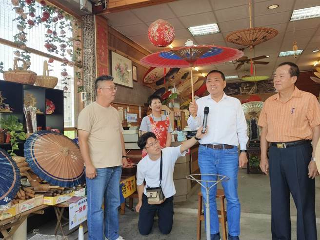 侯友宜到李家伞厂体验制作油纸伞，店家李师傅特地致赠侯中华民国伞，祝福任重道远，侯友宜拿起这把青天白日满地红的国旗油纸伞爱不释手，表示这把伞就像是代表中华民国，底下保护人民生命财产安全，他会勇敢担起来。（林雅惠摄）