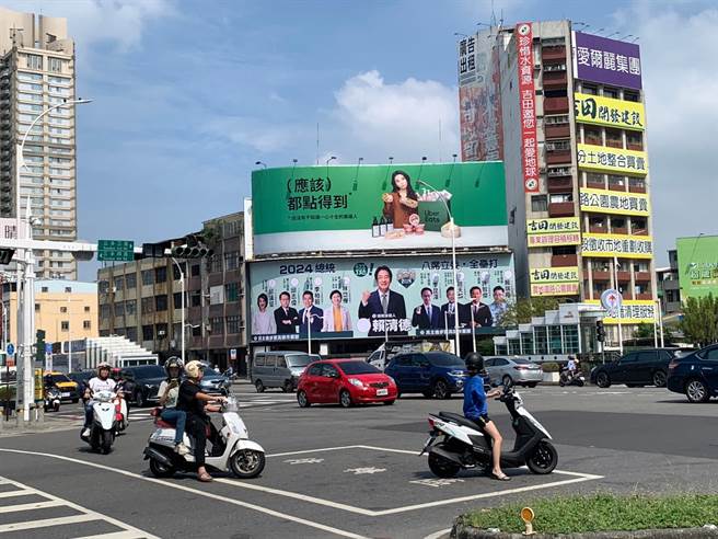 民進黨總統參選人賴清德與高雄8名小雞、立委參選人的聯合看板，今（21）日懸掛在南高雄的中山路、三多路大路口，巨大的橫幅，格外醒目，盼吸引選民眼球，力拚拿下總統、立委全壘打目標。（民進黨提供）