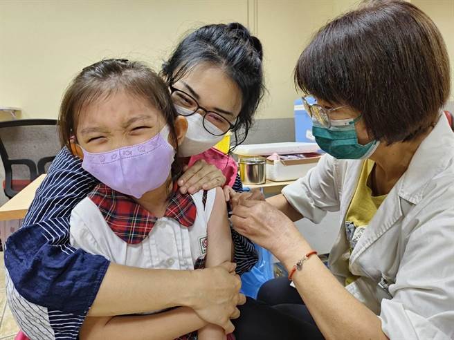 嘉義市博愛國小學生今天接種流感疫苗，小朋友緊張，教職人員給抱抱安撫。（廖素慧攝）