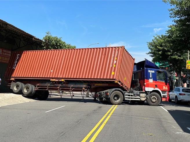 2023年10月24日新北市／43歲張姓駕駛表示，從地磅站過磅後欲轉彎離開時，因未算準轉彎角度及地磅站與平面道路高低差，造成貨櫃傾斜導致後輪卡住無法動彈，也不敢擅自處理怕貨櫃翻覆。（新北市樹林警分局提供／劉瑋晴新北傳真）