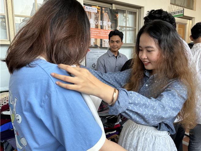 金大境外学生课余后聚在国际处办公室挑选、试穿爱心冬衣，拿到合身的衣物也开心极了。(于家麒摄)