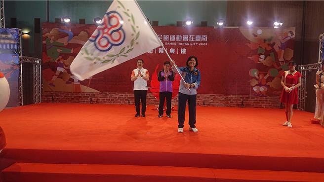 台南市全運會26日在大台南會展中心舉行閉幕典禮，台南市長黃偉哲（左一）將全運會會旗交給雲林縣長張麗善（右），張麗善當場揮舞會旗。（程炳璋攝）