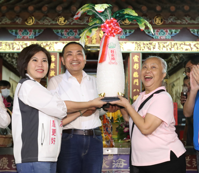 國民黨總統參選人侯友宜（中）27日赴台北市霞海城隍廟參拜，在當地熱情民眾的簇擁下同聲高喊凍蒜。 （鄭任南攝）
