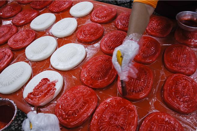 獅潭鄉新店社區27日在義民廟舉辦打新丁粄活動，社區志工為壓印完成的新丁粄上色。（黃子明攝）