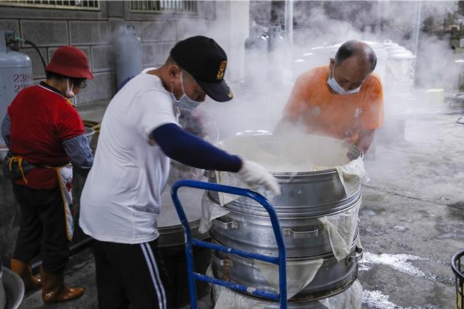 獅潭鄉新店社區27日在義民廟舉辦打新丁粄活動，志工將蒸煮後的米原料送去攪拌。（黃子明攝）