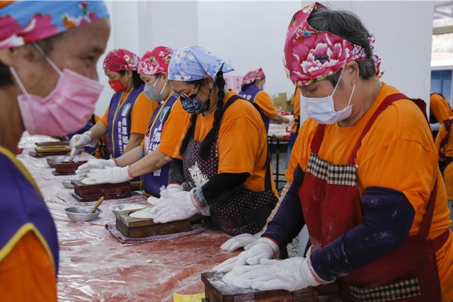 獅潭鄉新店社區27日在義民廟舉辦打新丁粄活動，志工將蒸熟的原料壓製成不同圖案的新丁粄。（黃子明攝）