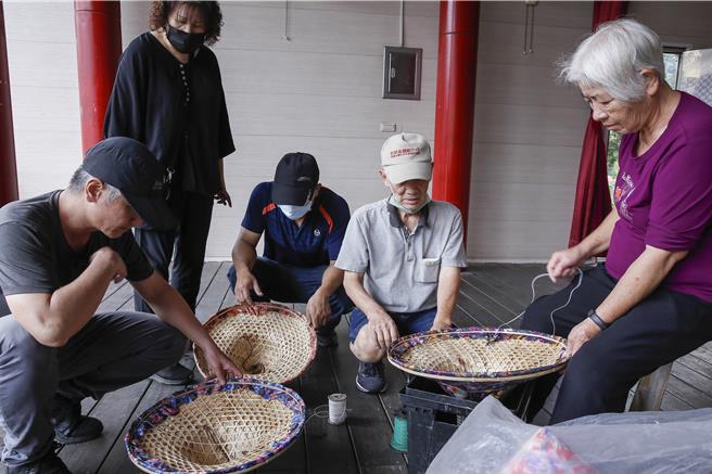 獅潭鄉新店社區27日在義民廟舉辦打新丁粄活動，28日有敬拜天神儀式與八音配樂、戲曲班等表演，以及生態體驗及農特產品展售，志工們正在戲台上布置套上客家花布的斗笠。（黃子明攝）