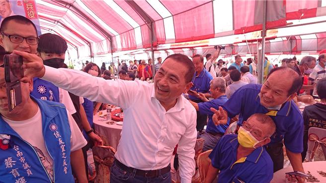 台南市新營太子宮28日中午舉辦平安宴，國民黨總統參選人侯友宜（右六）走入餐桌，民眾爭求合影，並一起玩自拍。（程炳璋攝）