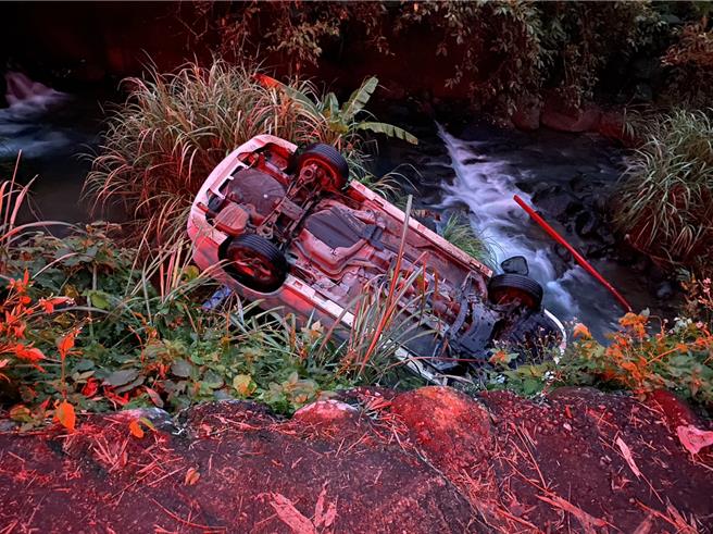 新北金山一辆小客车疑路况不熟，车子四轮朝天翻落溪河，居民架梯子协助救援受困的2名男子。（翻摄画面）