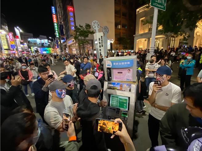 「新政治提款機」人裝道具今晚7點參加萬聖大遊行時準時，多名臉譜人圍在一旁，其中1人還不時抽菸。（陳育賢）