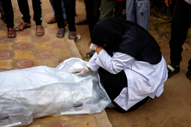 加薩走廊南部甘尤尼斯（Khan Younis）一名護理師因以色列空襲喪生，她的同事27日撫屍痛哭。（路透）